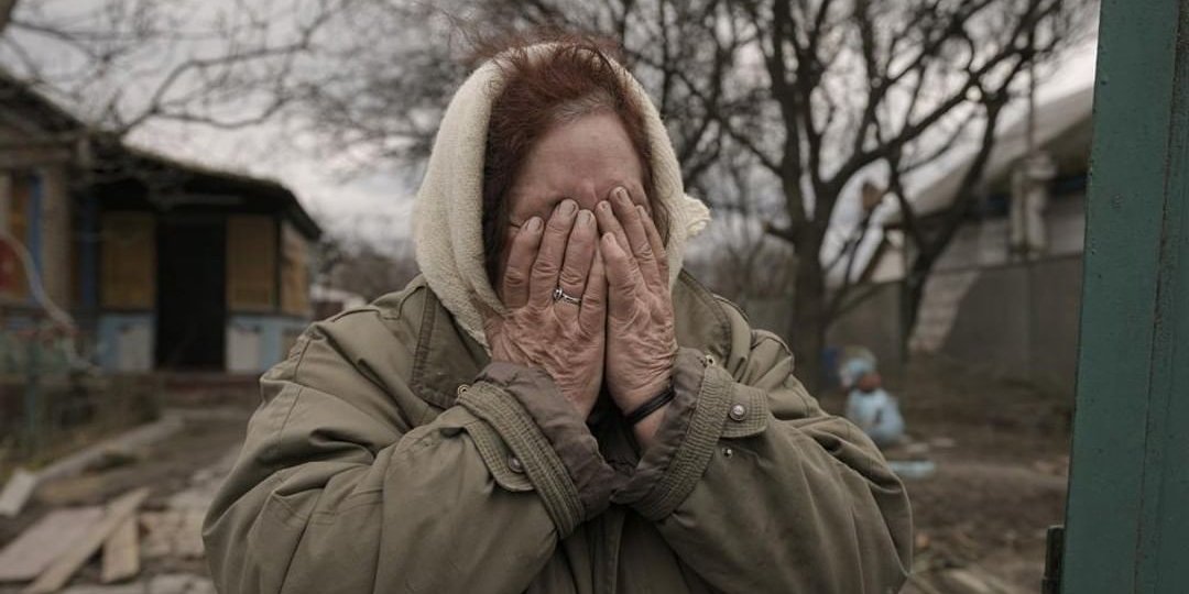 Тетяна Олексієнко плаче, стоячи біля воріт свого будинку в&nbsp;селі Андріївка (Фото: AP&nbsp;Photo/Вадим Гірда)