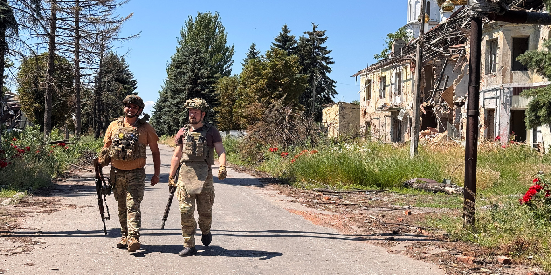 Українські військовослужбовці у&nbsp;повному спорядженні йдуть дорогою повз зруйновану обстрілами будівлю на&nbsp;Донеччині (Фото: Alex Nikitenko/Global Images Ukraine via Getty Images)