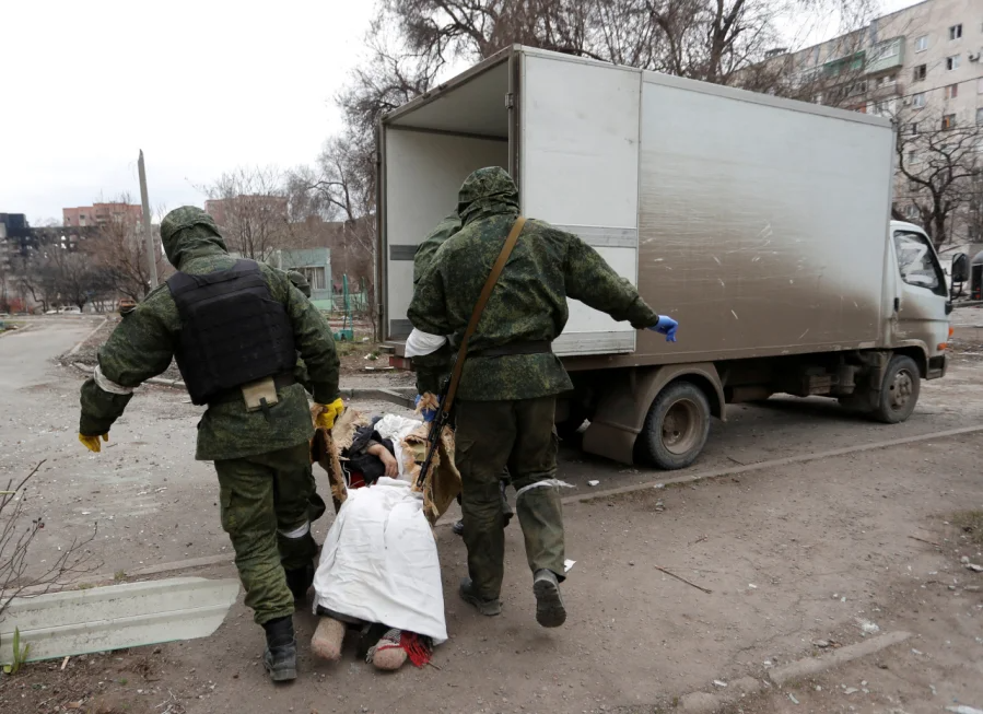 Russian occupiers carry a dead body of a local resident to a truck in Mariupol (Фото: REUTERS/Alexander Ermochenko TPX IMAGES OF THE DAY)