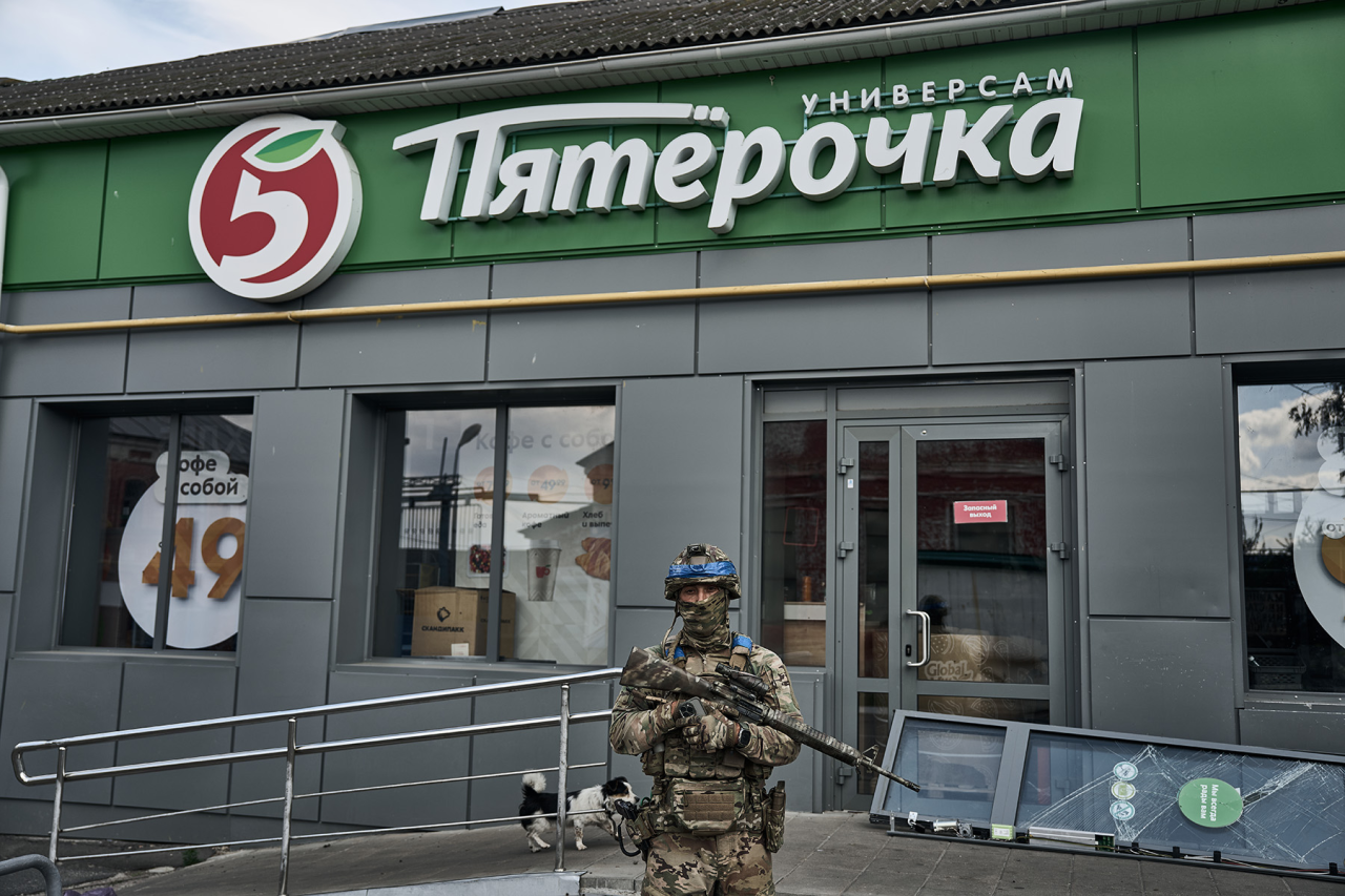 ПОРАБОТАЛИ НА ПЯТЕРОЧКУ: Украинский военный позирует на фоне магазина российской сети универсамов (Фото: Константин Либеров / Libkos / Getty Images)